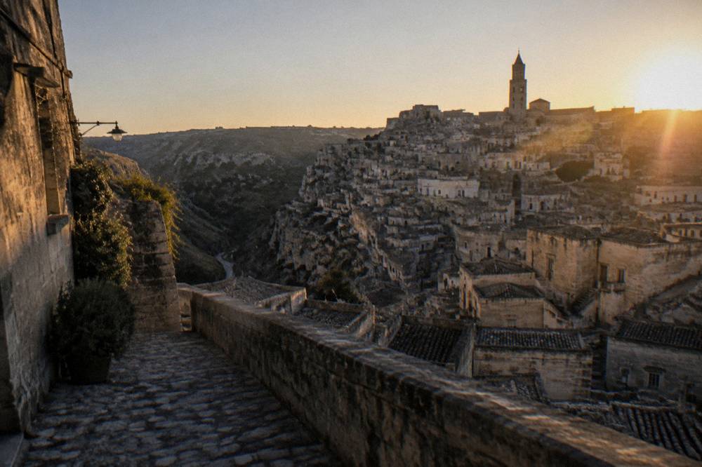 A panoramic viewpoint over a ravine with dense stone buildings at golden hour