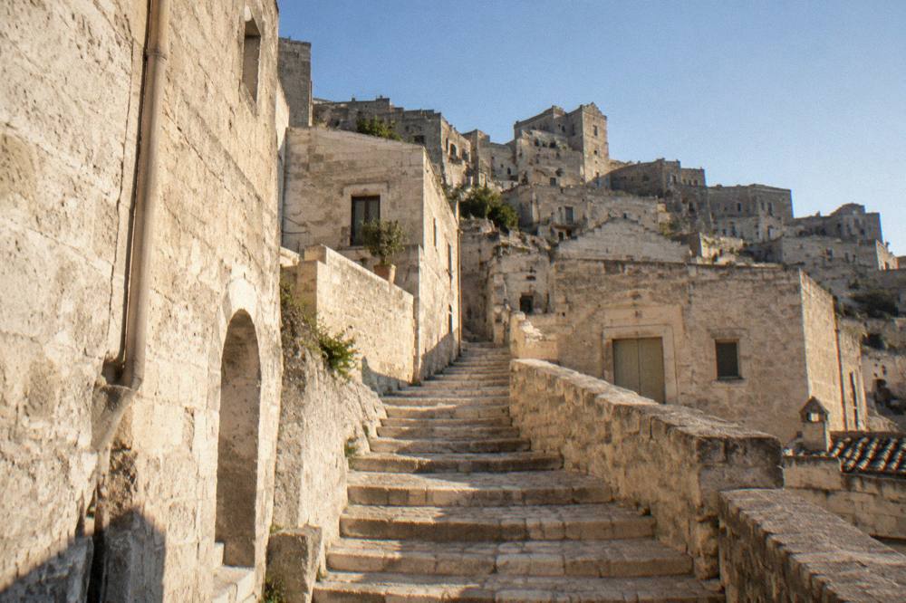An empty stone staircase between pale buildings in warm late-afternoon light