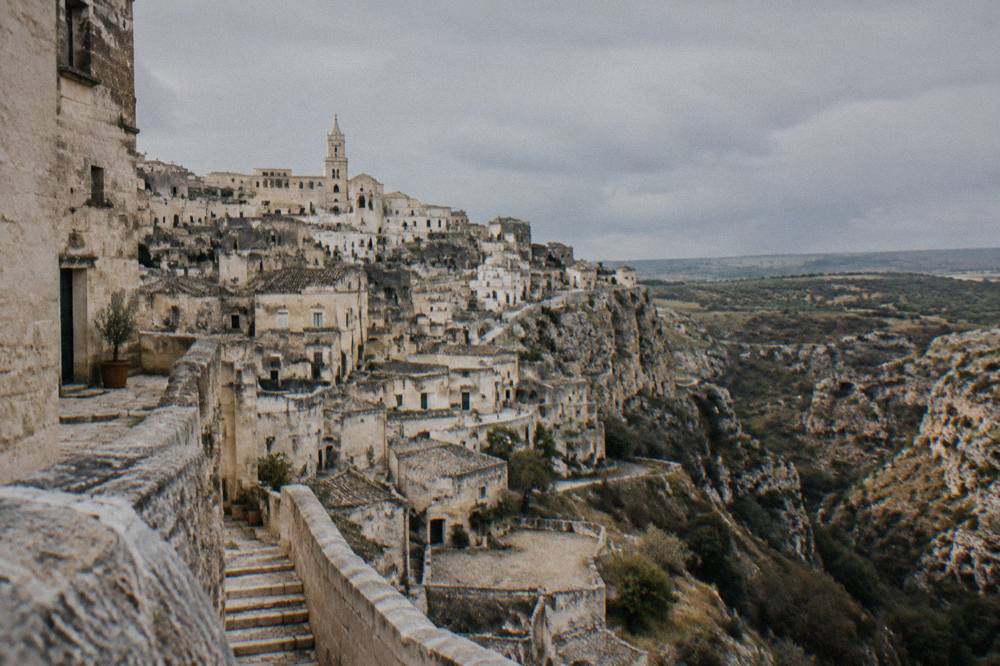 A white-walled hilltop town overlooking olive plains under a wide sky