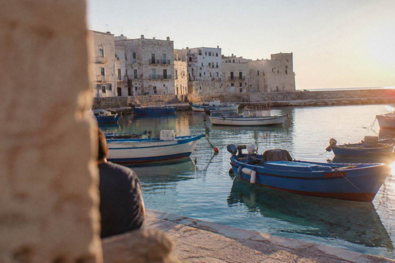 Fishing boats moored in the clear water of a small Adriatic harbour lined with pale stone buildings