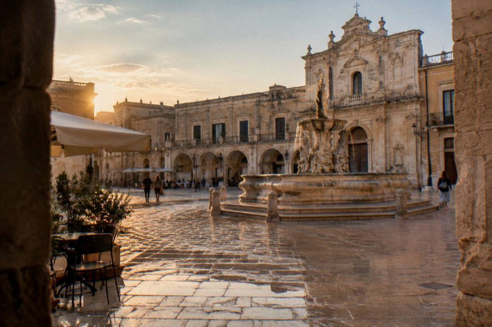 Evening light on a piazza with limestone facades in a Salento town