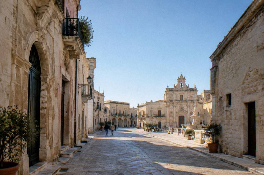 A quiet lane of stone houses under a clear sky in Nardo