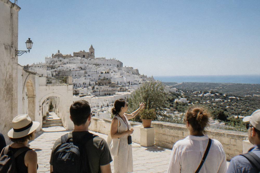 Small group of visitors listening to a guide in a sunlit piazza