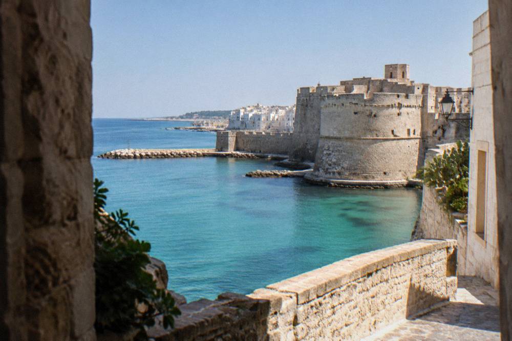 The thick stone walls and angular bastions of the Castello Aragonese in Otranto under a clear sky