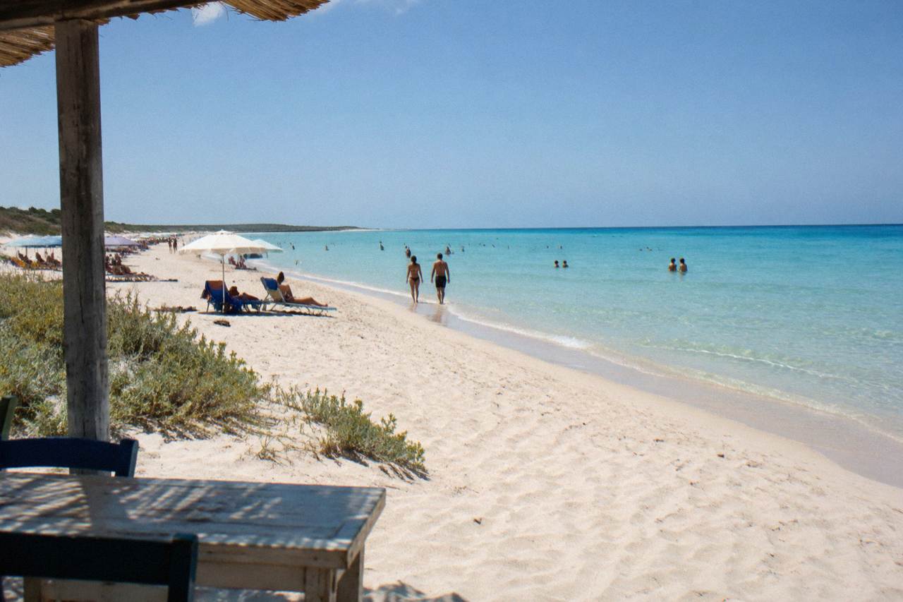 Wide beach of pale sand and shallow turquoise water at Pescoluse under a summer sky