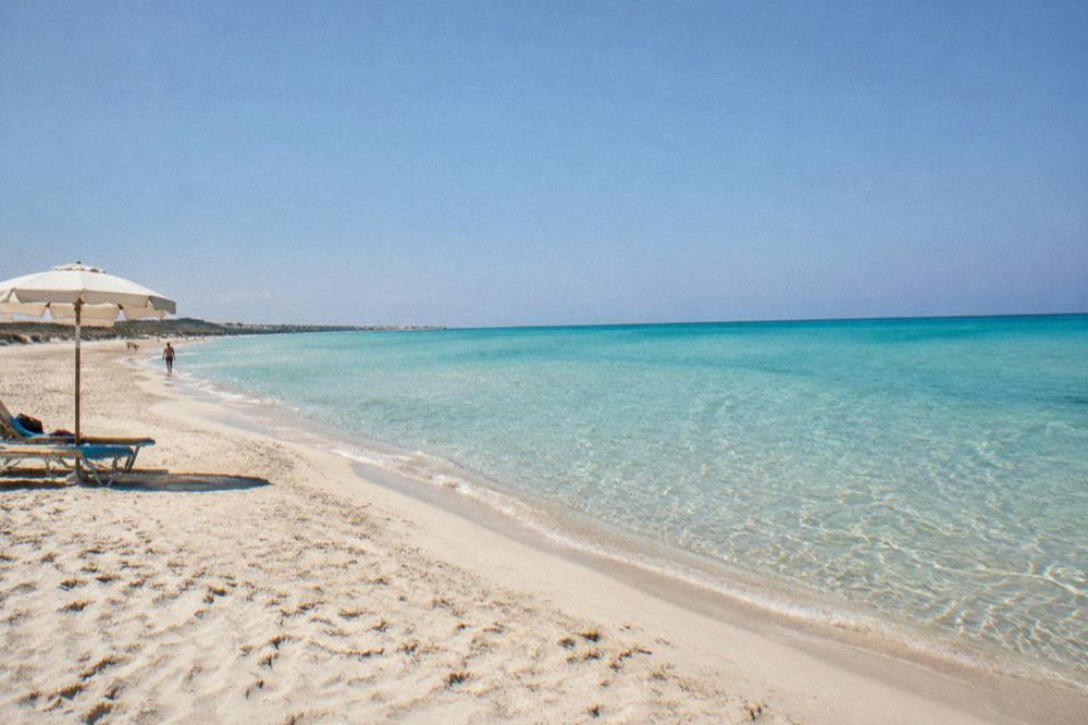 Turquoise shallow sea at Pescoluse seen from the sand at midday