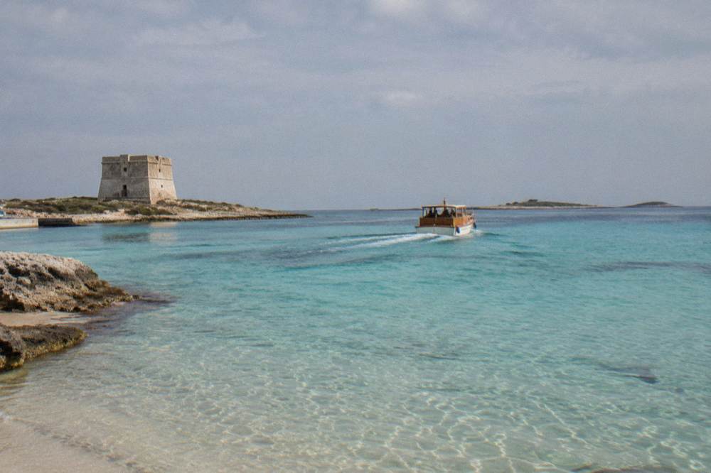 A wooden motorboat leaving Porto Cesareo harbour towards open water
