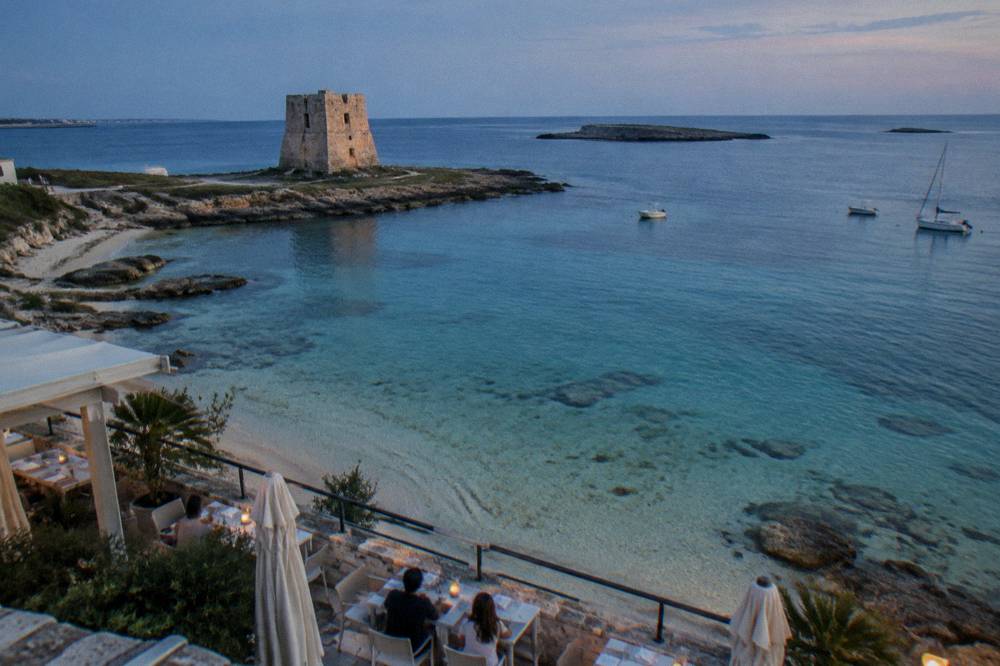 A seaside restaurant terrace with tables set for lunch overlooking the harbour