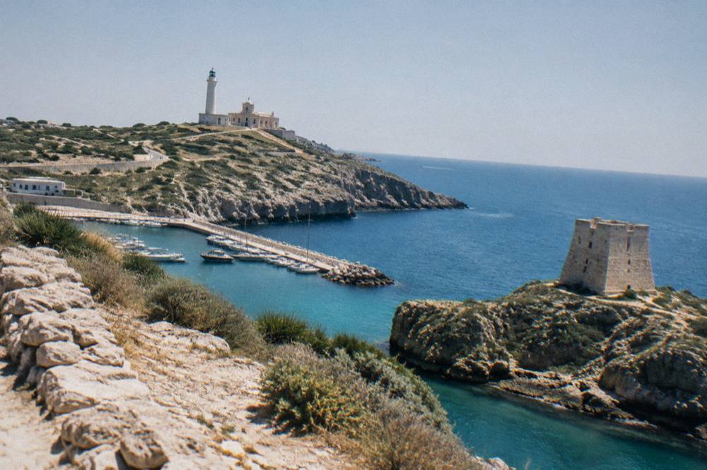 A stone watchtower on a rocky headland above clear blue Adriatic water