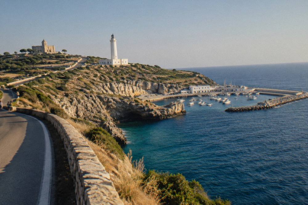 A coastal road curving along a low cliff above the sea at the southern edge of Puglia