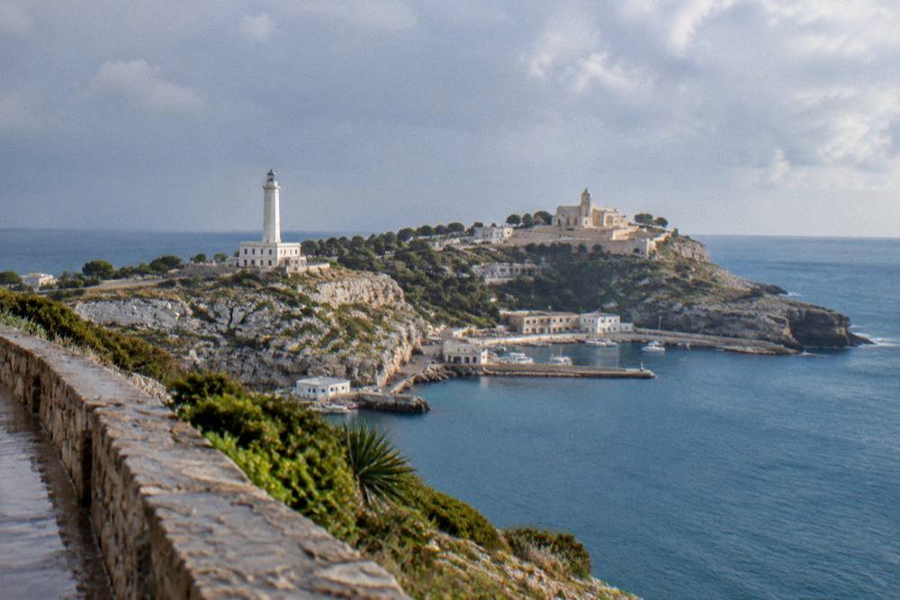 The view from a headland over two stretches of sea meeting beneath a pale church