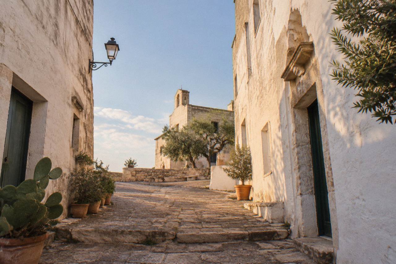 A narrow stone lane in a small Salento hill village with whitewashed walls and warm evening light