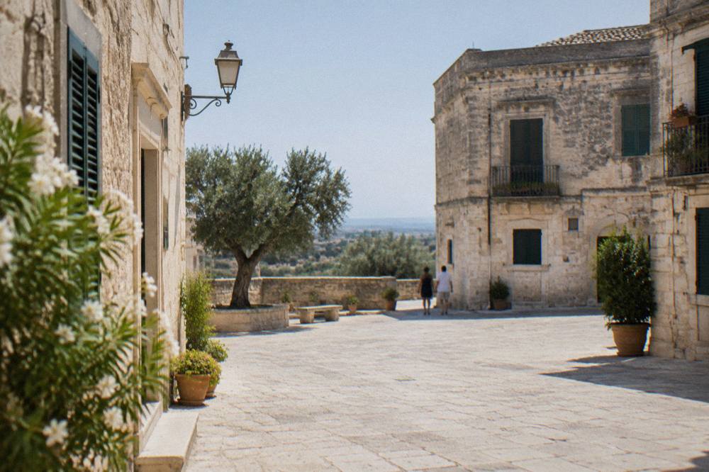 Old stone houses with green shutters around a small village square in southern Puglia