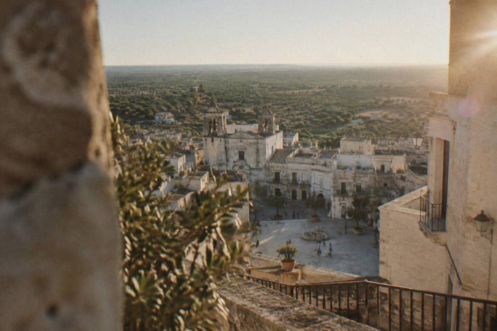 An aerial view of a compact hill village surrounded by olive groves in southern Puglia