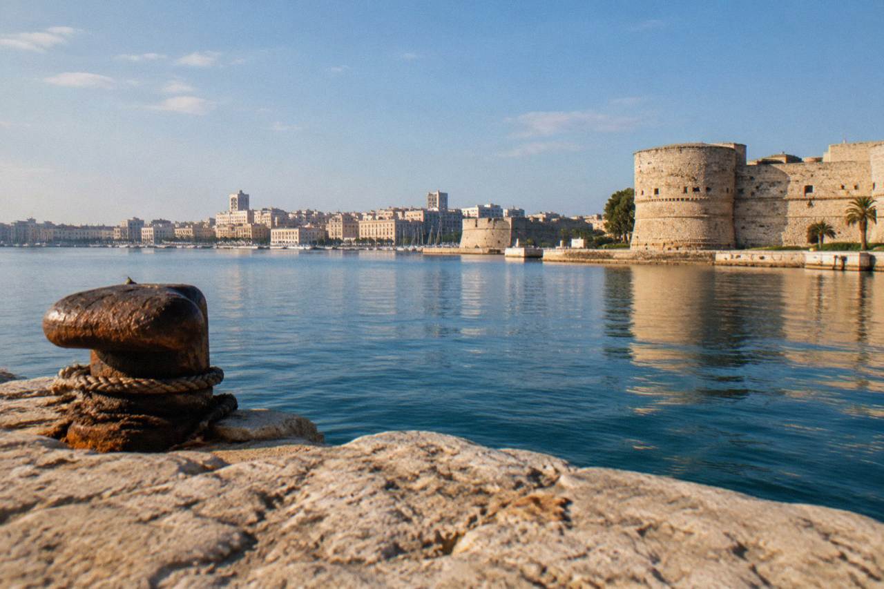 View across a harbour to a low Italian city skyline in warm afternoon light