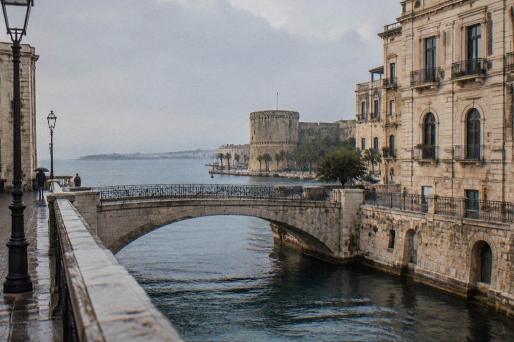 Stone bridge crossing a narrow channel between old buildings