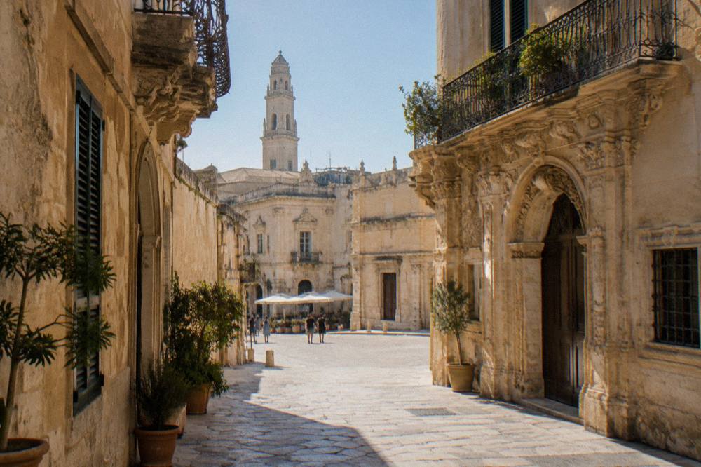 A walled old town by the sea with a cathedral bell tower and narrow stone streets