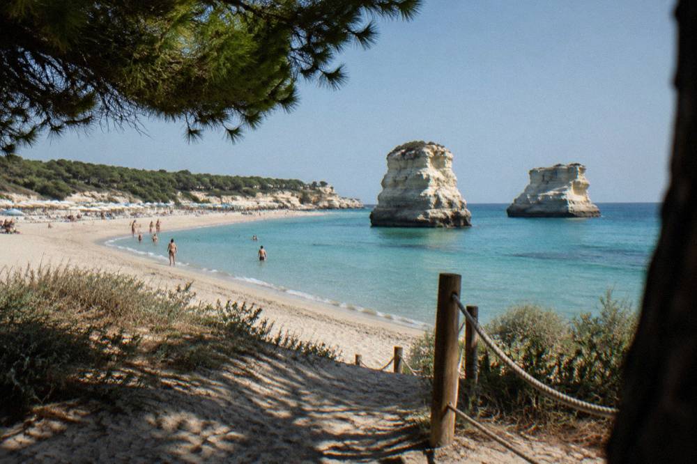 A wide sandy beach with dunes and beach umbrellas at Torre dell'Orso