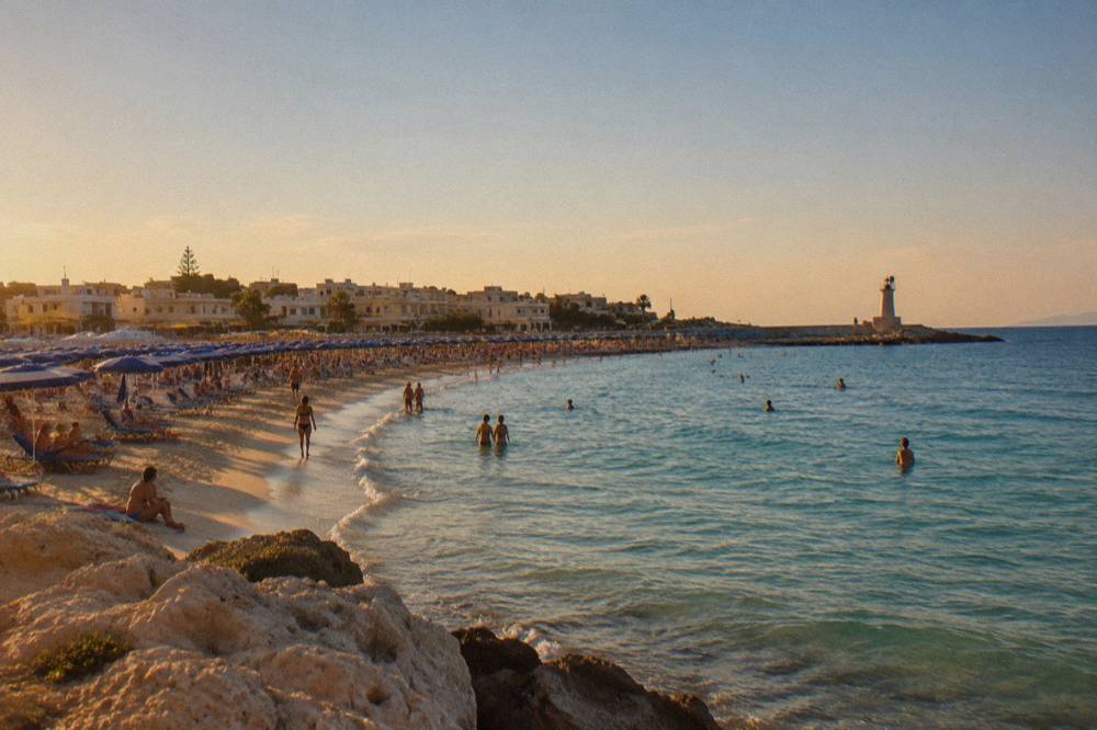 Rows of sun umbrellas and sunbeds on a crowded lido beach in August