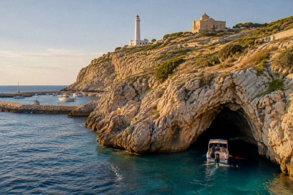 A small boat entering a sea cave with clear blue water near Santa Maria di Leuca