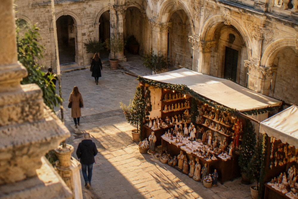 A Christmas market stall with handcrafted papier mache figures inside an ornate cloister in Lecce