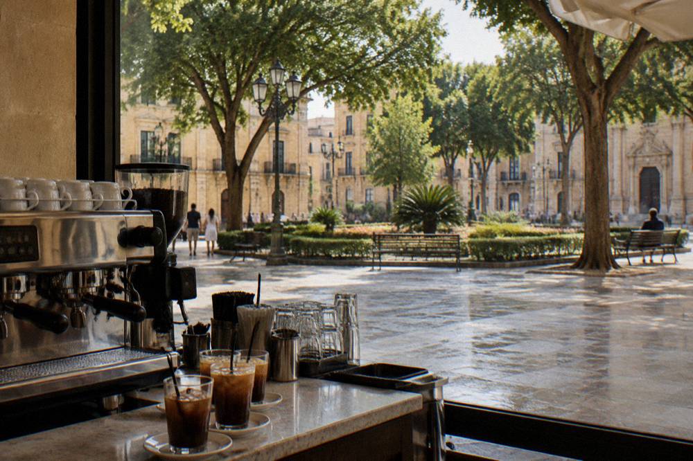 A historic Italian coffee bar counter with an espresso machine and glasses of iced coffee