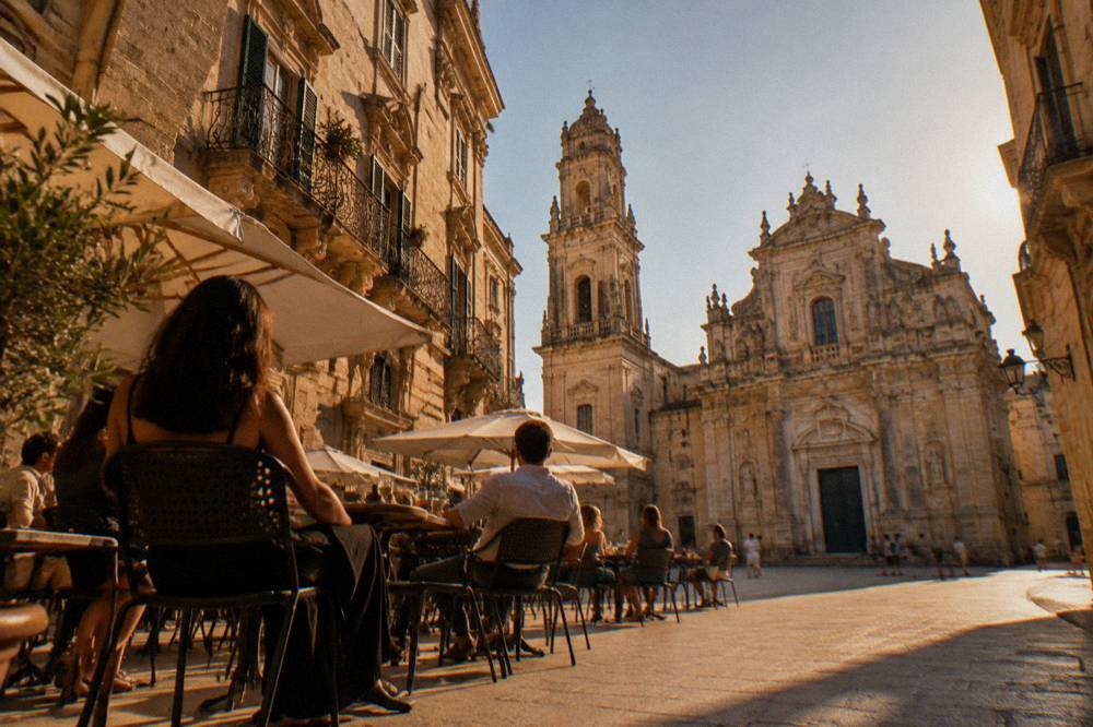 People at outdoor tables of a bar in a sunlit limestone square in Lecce