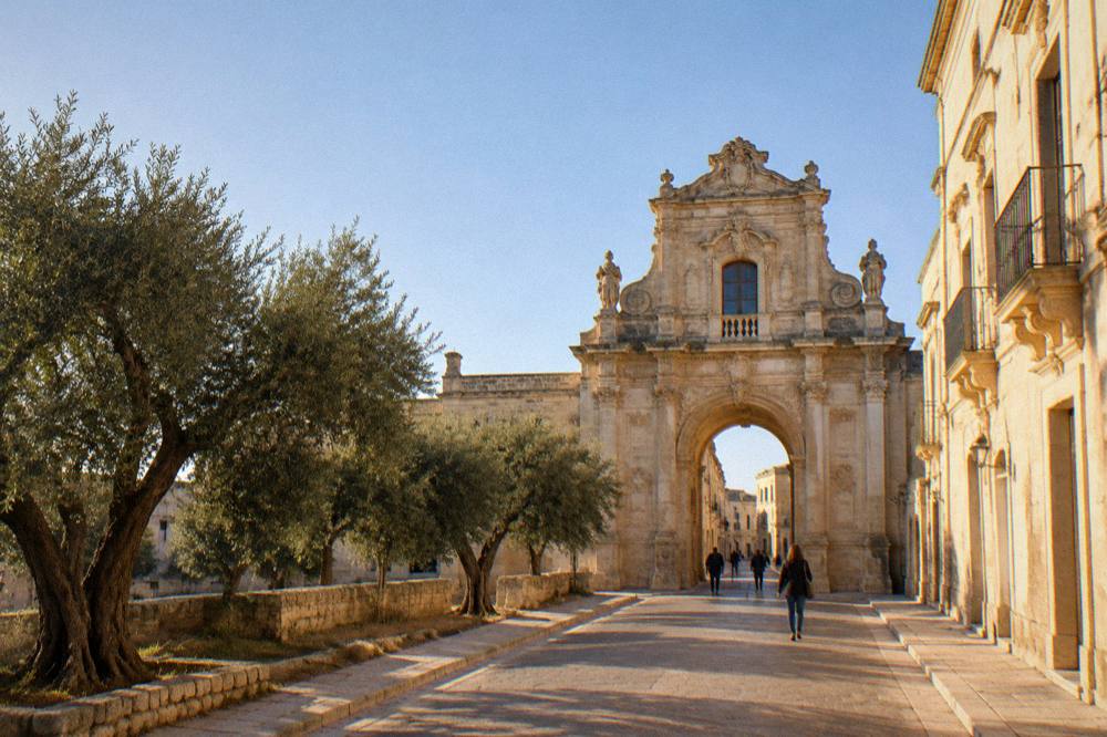 A straight country road lined with ancient olive trees under a wide sky in Salento