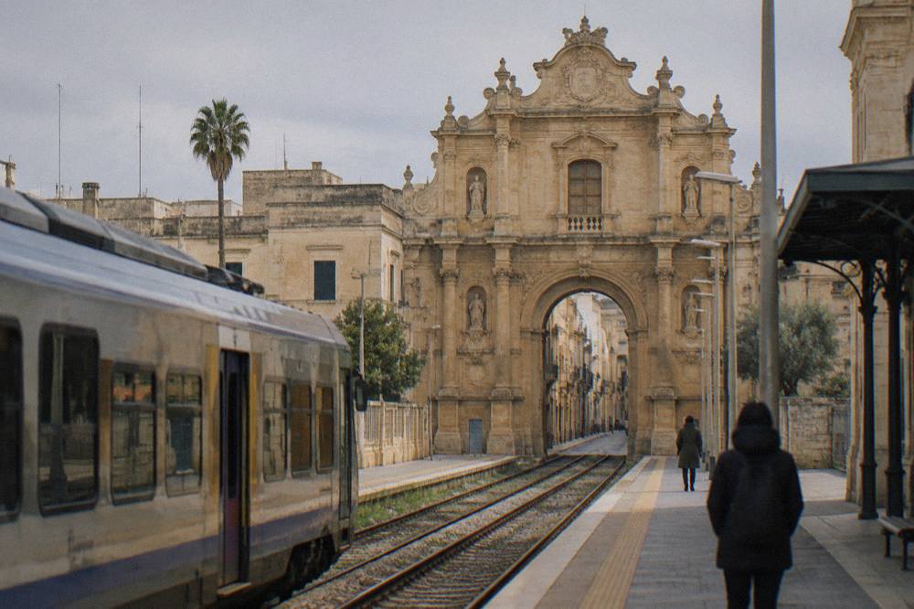 A regional train at a small southern Italian station platform in morning light