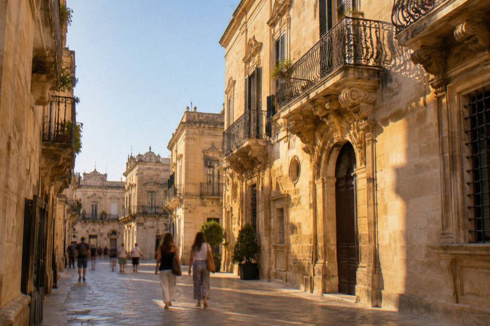 Visitors walking a narrow lane of baroque buildings in Lecce historic centre