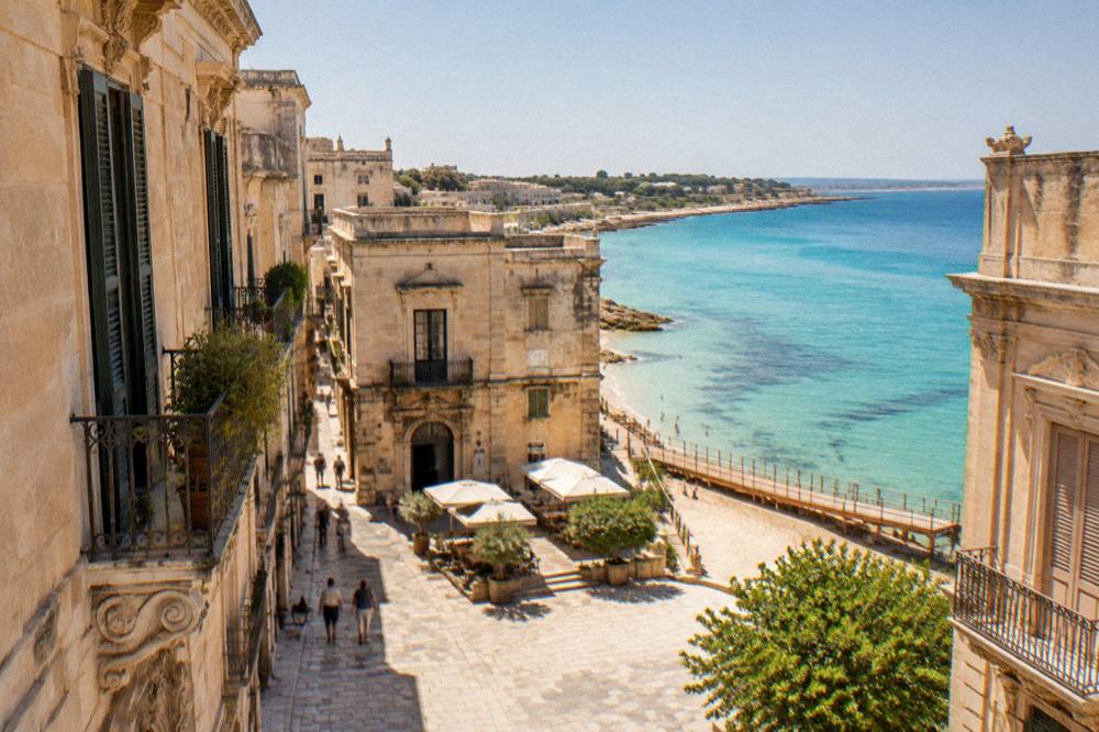 Turquoise shallow water over sand at a Salento beach with a wooden walkway
