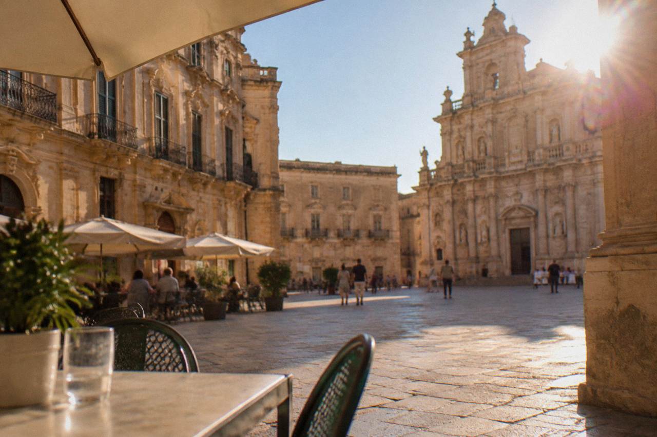 A sunlit square in Lecce with honey-coloured baroque facades and cafe tables
