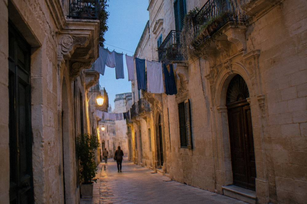 A narrow street in Lecce's old town with warm stone walls and laundry overhead