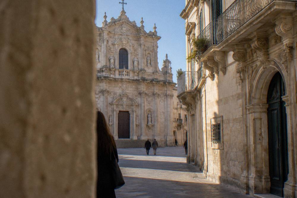 The ornate limestone facade of a baroque church in Lecce under a clear sky