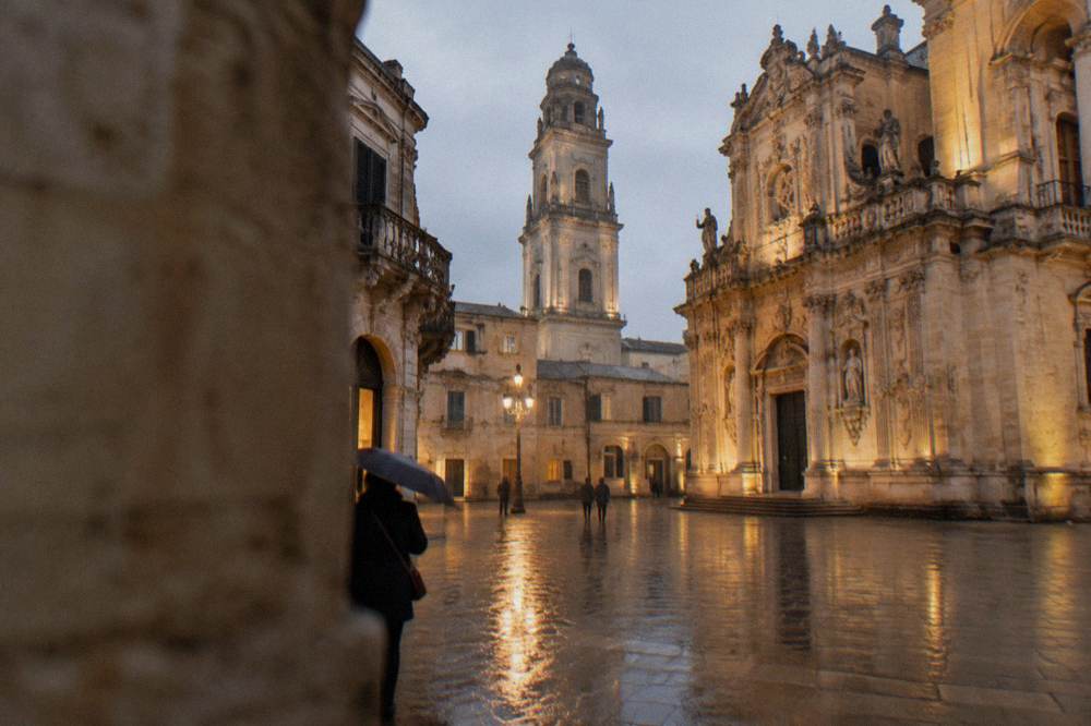 A lit cathedral square in Lecce on a December evening with few people around