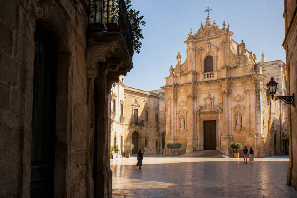 An illuminated baroque church facade in Lecce seen from a quiet evening square