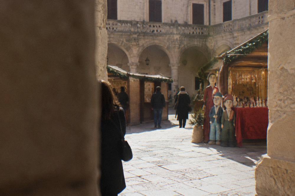 A Christmas fair in a Lecce cloister with lit stalls and papier mache figures