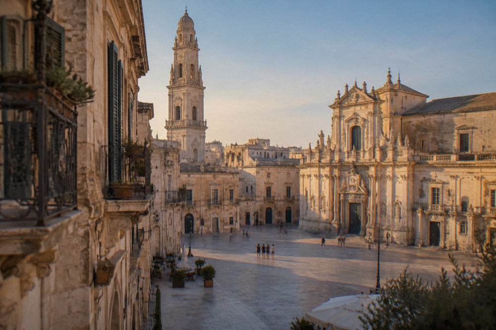 Sunlit piazza with a baroque cathedral and tall bell tower in Lecce