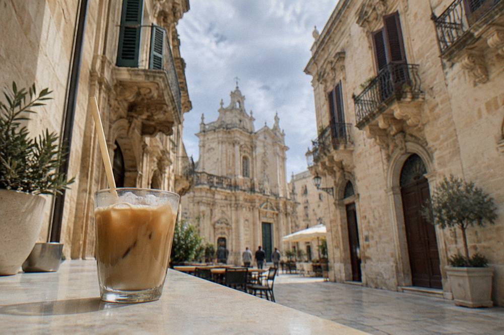 An iced coffee with almond milk in a glass on a cafe counter in Lecce