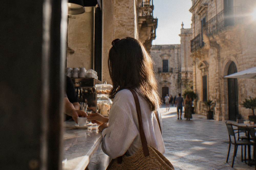 A customer standing at a marble cafe counter receiving an espresso in Lecce