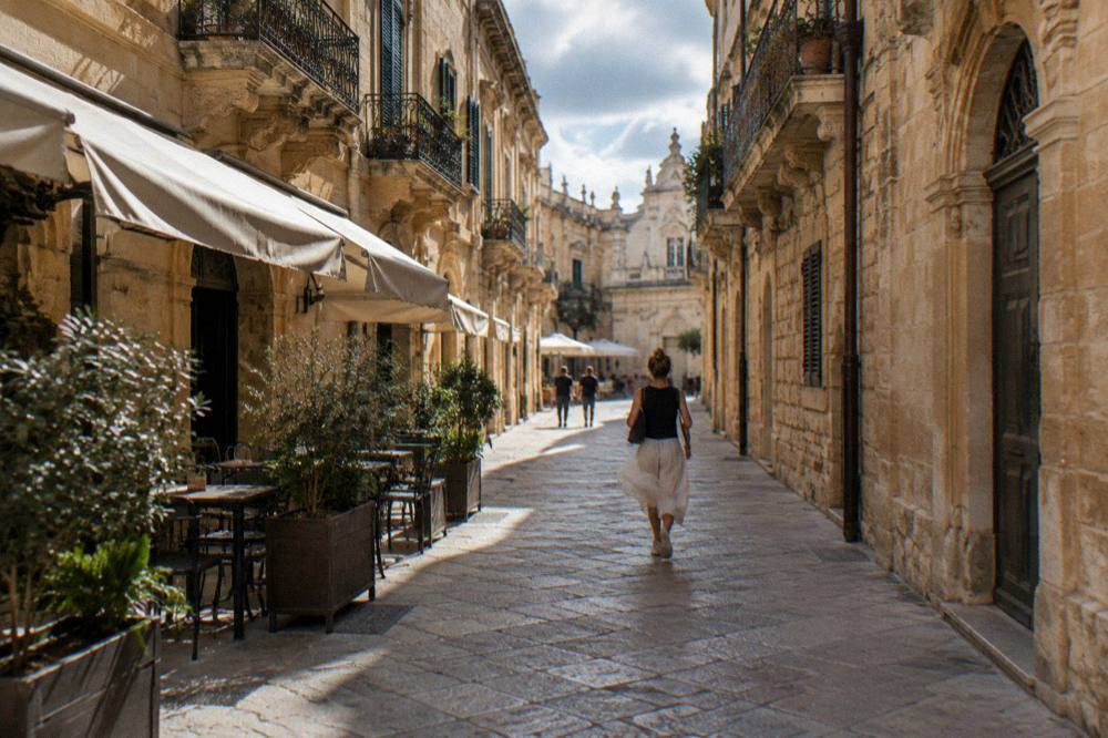 A narrow baroque street with cafe awnings and limestone facades in Lecce