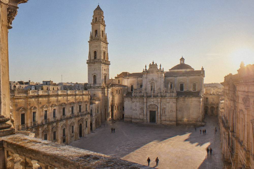 The twin facade and bell tower of Lecce Cathedral seen across Piazza del Duomo