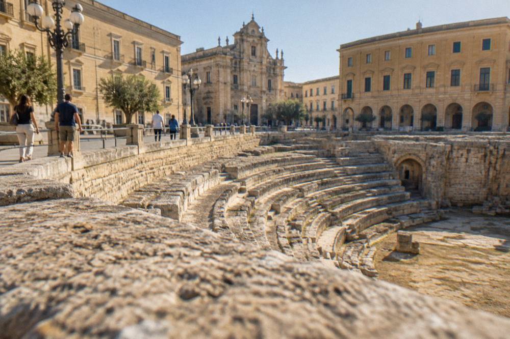 Visitors walking past the Roman Amphitheatre excavations in Piazza Sant'Oronzo in Lecce