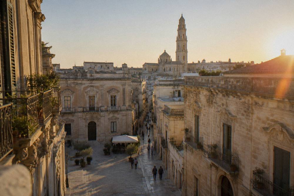 Lecce Cathedral bell tower rising above rooftops under a clear evening sky
