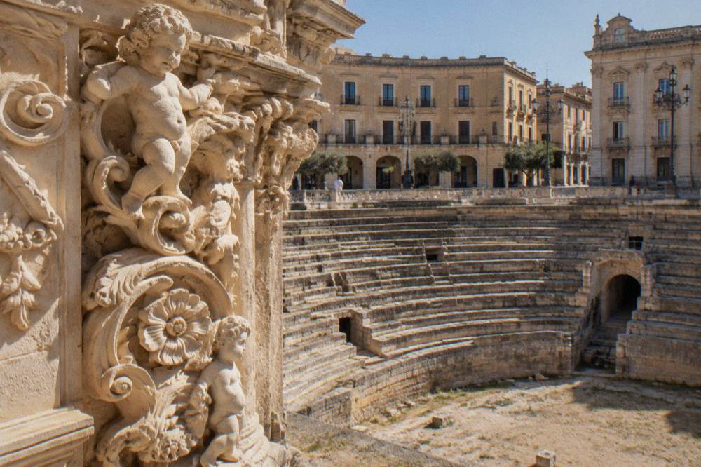 Close view of a deeply carved limestone facade with flowers, cherubs and scrolling detail