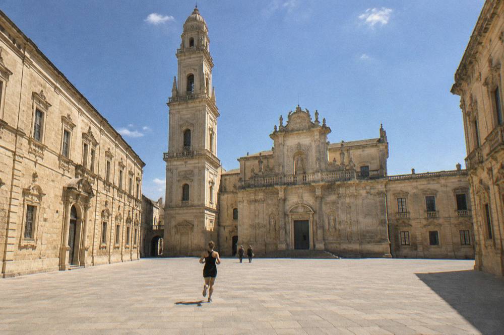 The facade of the Duomo in Lecce under an autumn sky with few people around