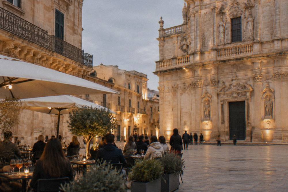 Evening light on a baroque square in Lecce with people at outdoor tables