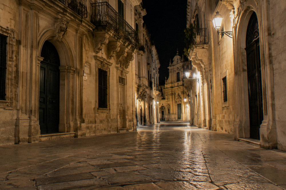 An empty lit street in Lecce's old town late at night with baroque buildings on both sides
