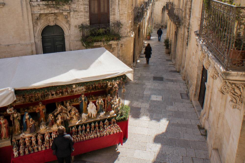 A Christmas market stall in Lecce displaying painted papier mache nativity figures