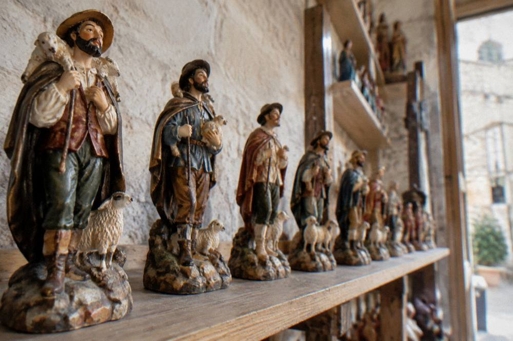 A row of finished painted papier mache shepherd figures on a workshop shelf